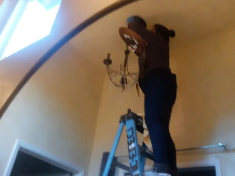 Electrician installing a chandelier in a Chesaning residence
